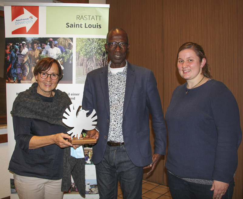 Uschi Böss-Walter (links) übergab Mamadou Mbodji, Koordinator des Mangrovenaufforstungsprojekts, eine Friedenstaube und dankte auch Übersetzerin Miriam Streit.